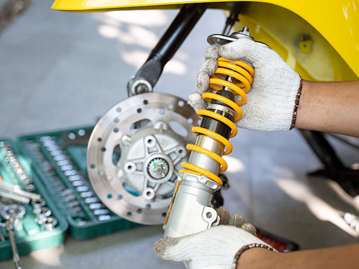 Vibration Testing, Vibration Analysis, and Mechanical Shock with a mechanic holding a yellow automotive shock in front of a router.