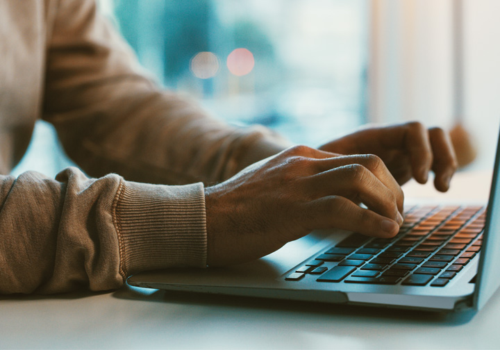 Hands typing on a laptop keyboard.