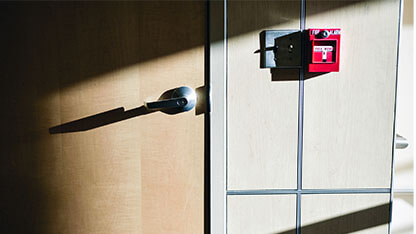 Commercial building door with fire alarm on the side beautifully lit by sunbeam